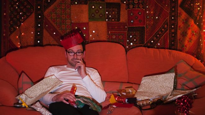 Man on couch wearing Christmas hat