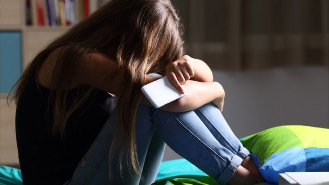 Teenager in her bedroom with her phone