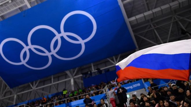 A Russian flag is waved in front of the Olympic rings at Pyeongchang 2018