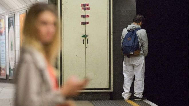 Мужчина мочится на дорожках внутри на станции метро Оксфордского цирка
