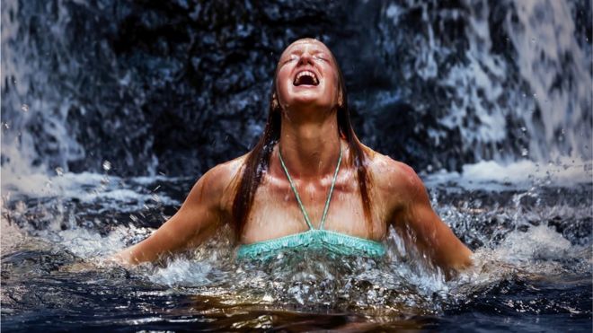 Woman looking exhilarated coming out of cold water