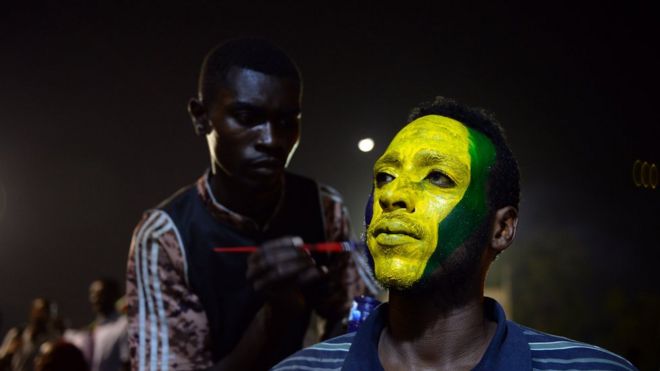 Протестующий, у которого его лицо окрашено в цвета старого суданского флага в Хартуме, Судан