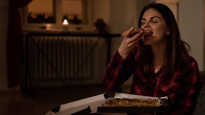Chica comiendo pizza de noche