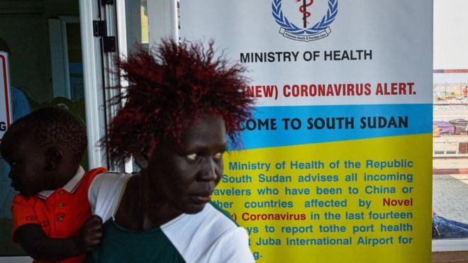 A passenger walks past a coronavirus health sign in South Sudan