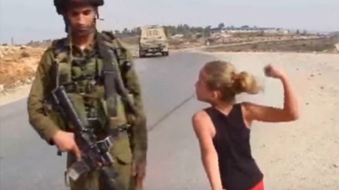 در این عکس هم عهد تمیمی که فقط ۱۱ سال دارد با مشت گره کرده سرباز اسرائیلی را تهدید می‌کند