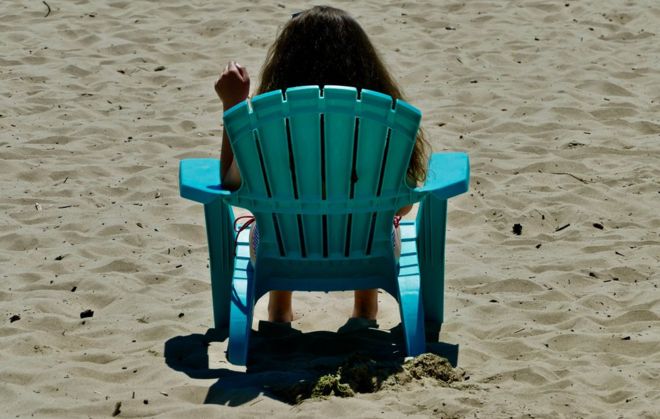 Девушка сидела на стуле на пляже в Борнмуте