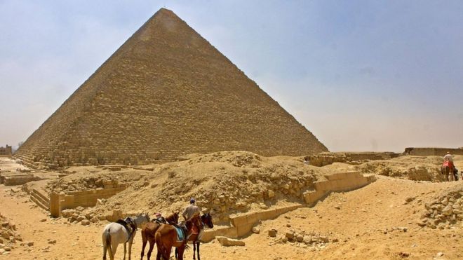 A horseman waits with his              horses for tourists in front of Egypt's Cheops Pyramid at              Giza plateau south of Cairo, 13 June 2002