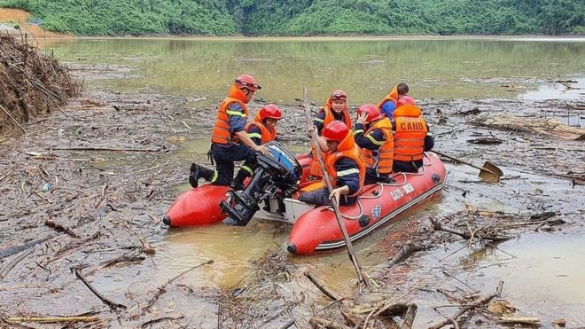 Các nhân viên tìm kiếm cứu nạn Việt Nam băng qua qua lòng hồ thủy điện Hương Điền tại xã Hương Bình, huyện Phong Điền để tìm kiếm các nạn nhân mất tích trong vụ sạt lở đất tại khu thủy điện Rào Trăng 3.