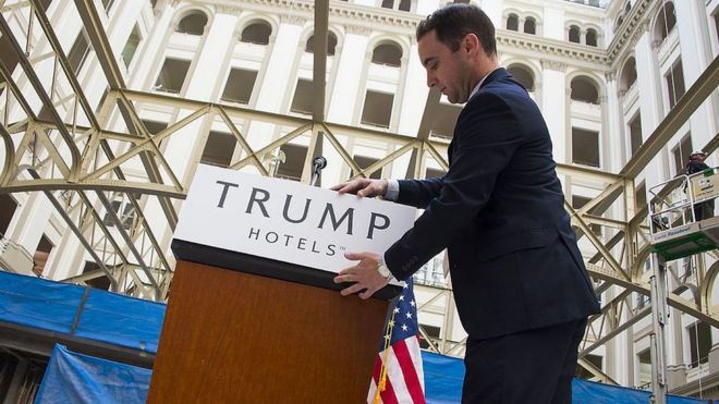 Сотрудник прикрепляет плакат к трибуне перед пресс-конференцией кандидата в президенты от республиканцев Дональда Трампа в строящемся отеле Trump International в Вашингтоне, 21 марта 2016 года.