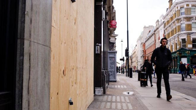 Мужчина проходит мимо заколоченного магазина на Мортимер-стрит в Лондоне, Англия, 2019 год.