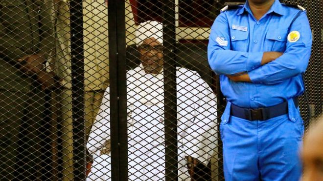 Former president of Sudan Omar al-Bashir, sitting in a cage during his sentencing