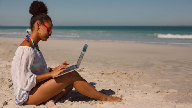Женщина на пляже с ноутбуком