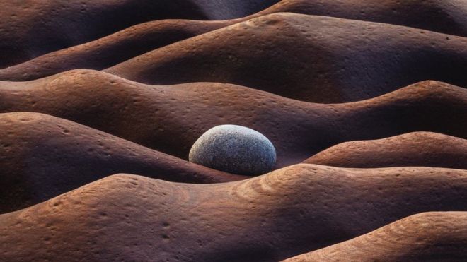 A photo showing a stone on an undulating ground