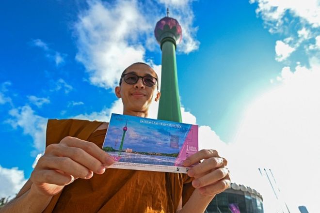 A Buddhist monk displays his entrance ticket to visit the Sri Lankan 'white elephant' Chinese-built Lotus Tower after it was opened for public in Colombo on September 15, 2022. (
