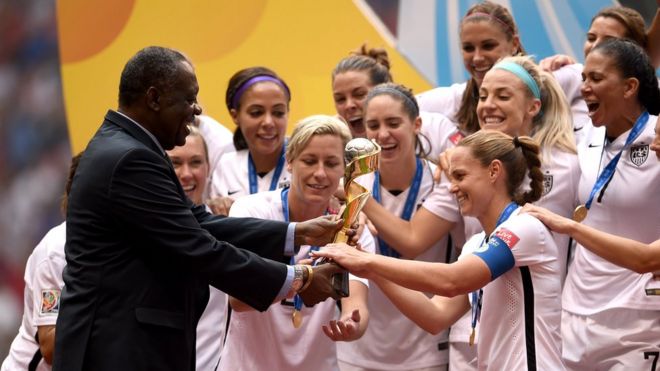 Старший вице-президент ФИФА из Африки Исса Хаяту вручает трофей Кубка мира по футболу женской сборной США по футболу, которая празднует победу на чемпионате мира по футболу среди женщин в Канаде 2015 со счетом 5-2 против Японии на стадионе BC Place 5 июля 2015 года в Ванкувере, Канада.