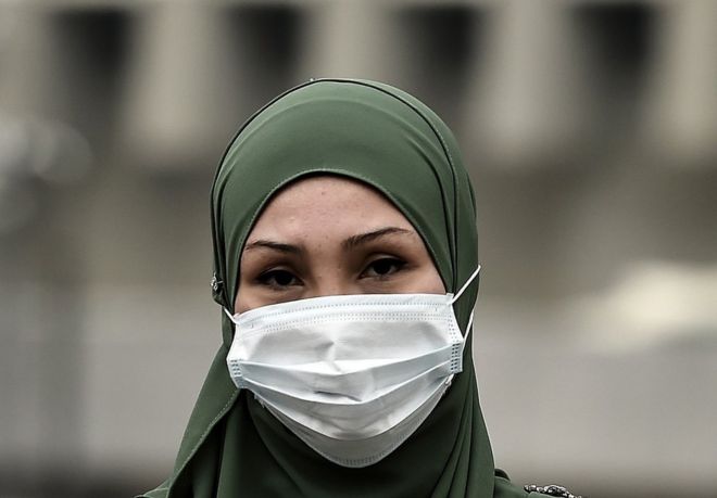 Малазийская мусульманка в маске пересекает дорогу в густой дымке над Куала-Лумпуром 15 сентября 2015 года.