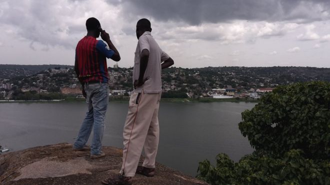 Два человека смотрят на Мванзу, Танзания, один по телефону