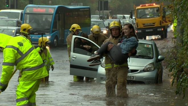 Пожарные помогают автомобилисту из машины во время наводнения