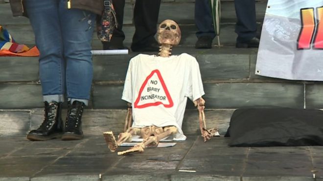 Скелет носит футболку с надписью «Нет Барри мусоросжигателя»