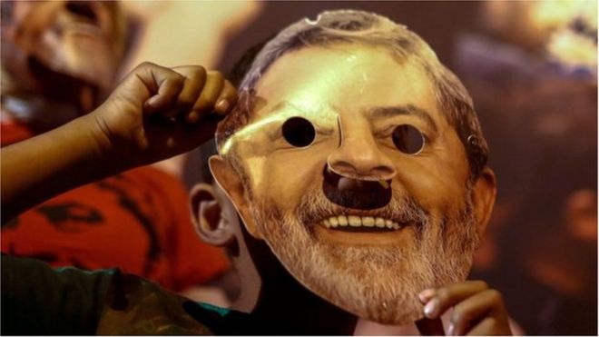 Militante com máscara de papel representando o rosto de Lula