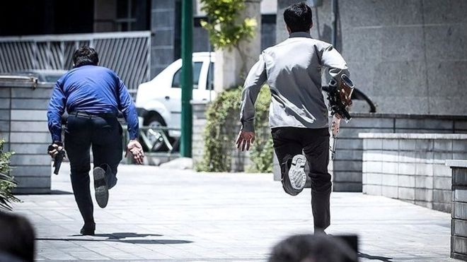 Miembros de las fuerzas de seguridad iraníes corren durante el ataque al Parlamento en Teherán