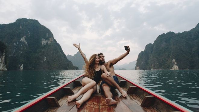 Self adoring couple taking a selfie on a longtail boat, on a spectacular setting