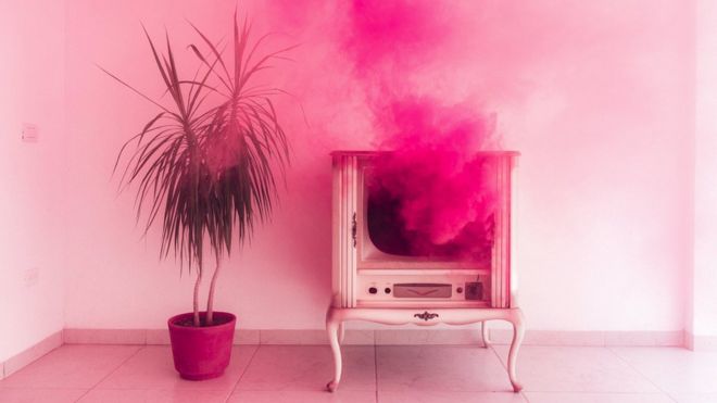 Concept image - a plume of pink smoke coming out from an antique tv set, with a plant next to it