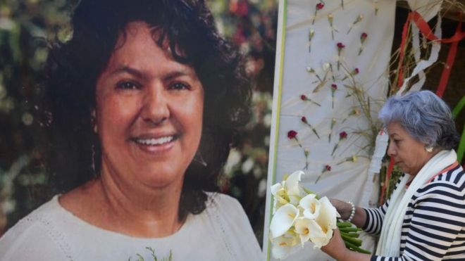 Foto de Berta Cáceres y una mujer dejándole flores.