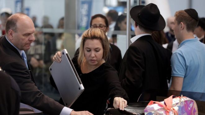 A woman putting a bag in a tray for screening at an airport