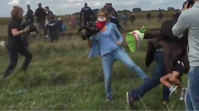 ハンガリーN1TVのカメラマンが、走り逃げる移民の親子をわざと足を引っ掛けて転ばせた。