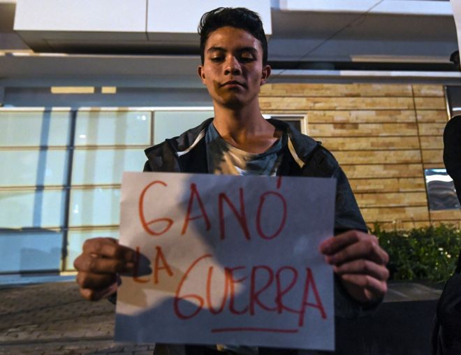 Joven con un cartel que dice: "Ganó la guerra"