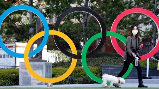 Woman with dog in front of Olympic rings. File photo