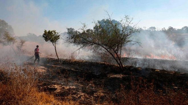 An Israeli fire fighter extinguishes a fire near Kibbutz, next to the Gaza Strip, caused by an incendiary balloon (19 August 2020)