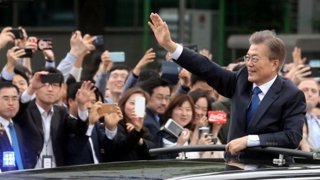 Президент Южной Кореи Мун Чже-ин (справа) машет рукой из машины, направляясь в президентский Голубой дом в Сеуле. Фото: 10 мая 2017 г.