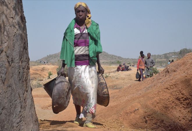 Женщина несет металлические сковородки на шахте "Баркин Лади"
