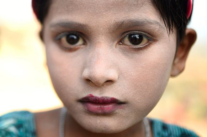 7-летняя беженка из рохингья Суфайда позирует фотографу, когда она носит пасту танака в лагере Кутупалонг на базаре Кокса, Бангладеш