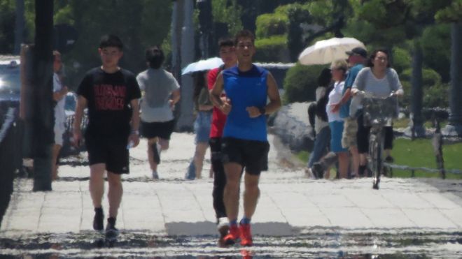 Последствия тепловой дымки видны, когда пешеходы идут по улице во время сильной жары в Токио 2 августа 2018 года