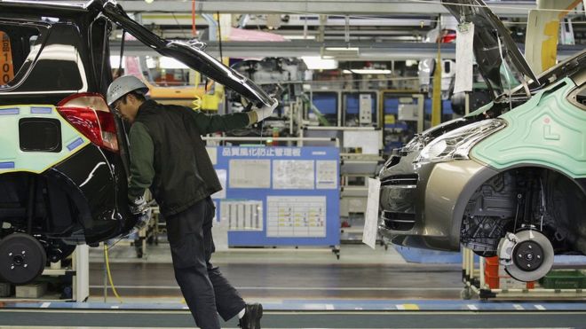 Человек смотрит в машину на производственной линии Toyota в Японии