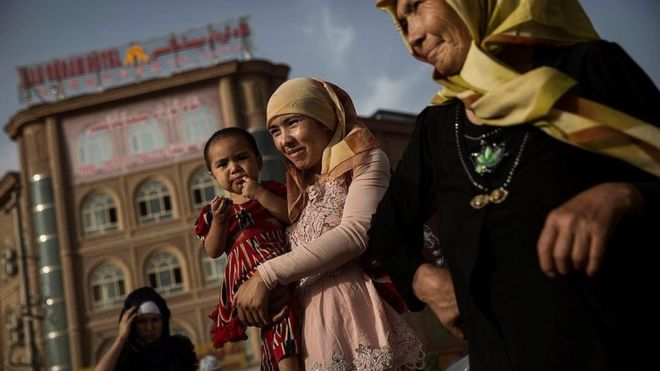 A Uyghur woman walks with her baby at a market on August 1, 2014 in old Kashgar, Xinjiang Uyghur Autonomous Region, China