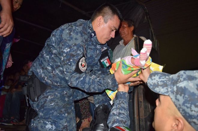 Un miembro de Protección Civil de Chiapas con un bebé entre las manos en Tapachula, en el sur de México.