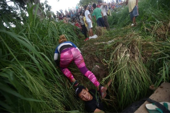 Женщина ползет на берег реки после пересечения реки Сушиате с помощью других мигрантов