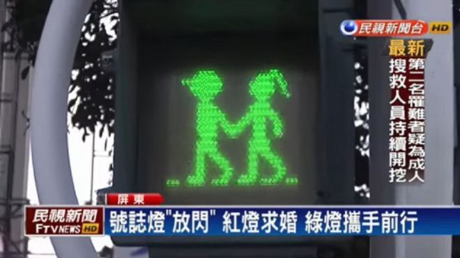 Saat lampu lalu lintas merah, rambu untuk pejalan kaki yang terpampang adalah gambar pria dan wanita yang bergandengan