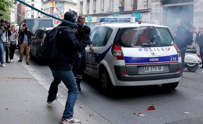 Протестующий бьет полицейского в штангу после нападения на полицейскую машину во время демонстрации в Париже, Франция (18 мая 2016 года)