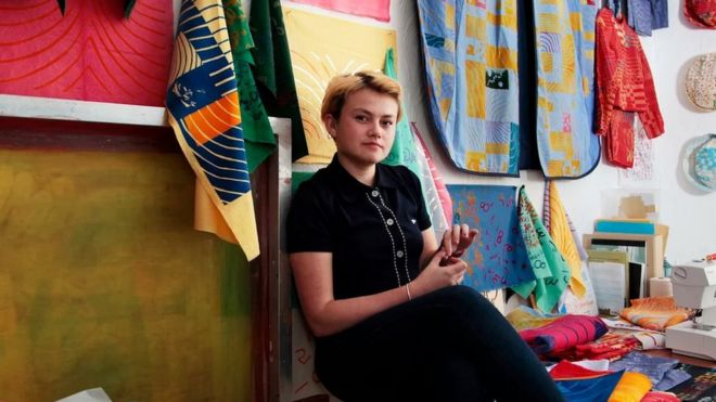 Poppy Nash sitting amongst her material designs