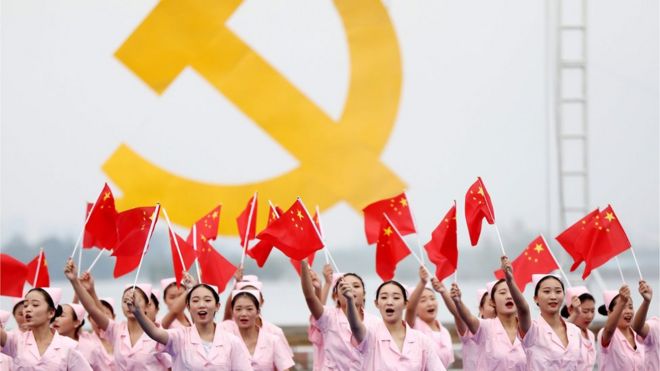 Mujeres chinas frente a un símbolo comunista