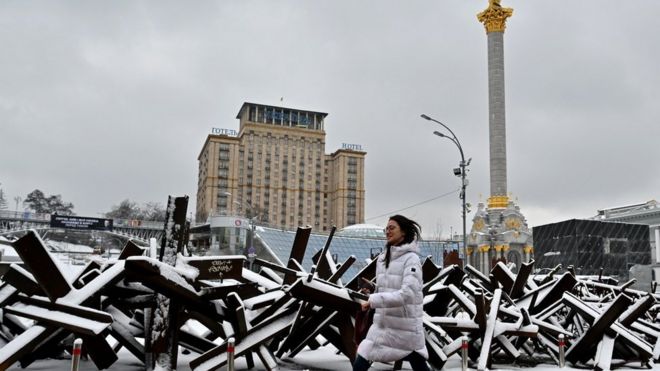 Una mujer camina por barricada antitanque en Kyiv.