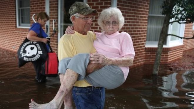 Bob Richling carries Iris Darden as water from the Little River starts to seep into her home in Spring Lake, North Carolina.
