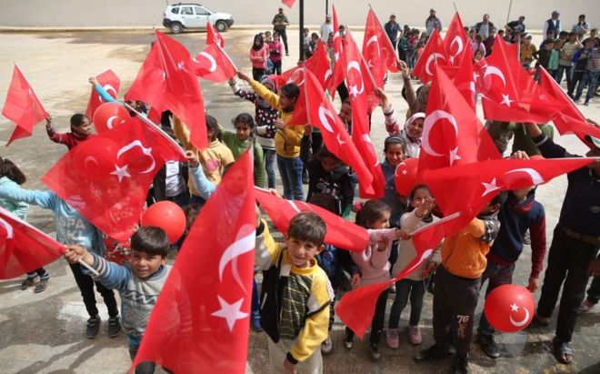 احتفال الأطفال وهم رافعين العلم التركي، مع غياب الأعلام السورية، في إحدى قرى عفرين بعد سيطرة الجيش التركي والفصائل الموالية له. 26 مارس/آذار 2018