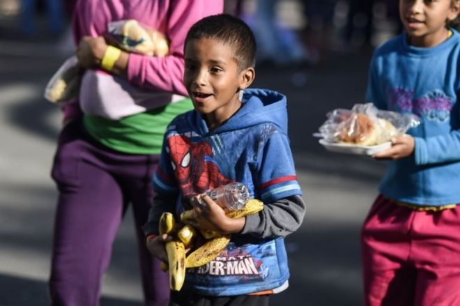 Дети-мигранты несут бананы и другие продукты питания на спортивном стадионе в Мехико, где они укрываются