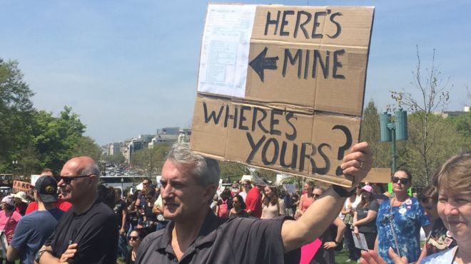 Демонстрант на Налоговом марше в Вашингтоне, округ Колумбия, держит плакат с надписью: «Вот мой, а где твой?»
